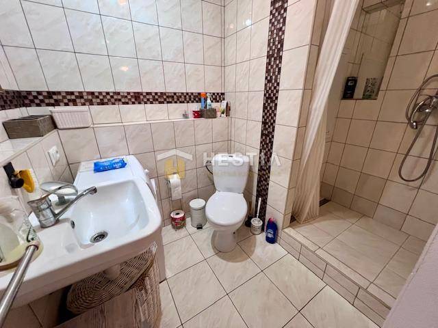 Badezimmer in einer 2-Zimmer-Wohnung mit Toilette, Dusche und Waschbecken.