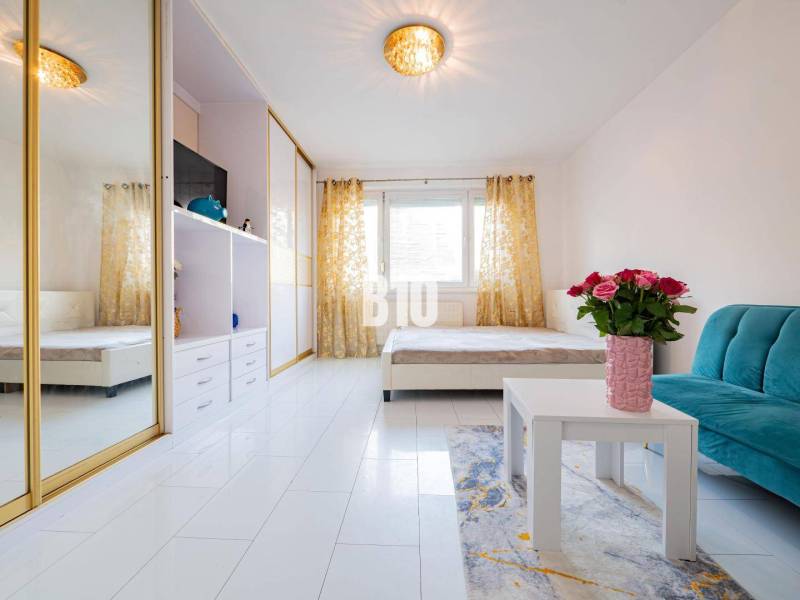 Wohnzimmer in einer Einzimmerwohnung mit einem Spiegelschrank und weißen Böden.