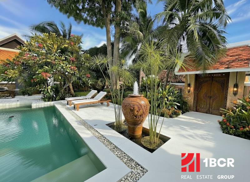 Blick auf eine Luxusvilla in Pattaya mit Pool und exotischem Garten.