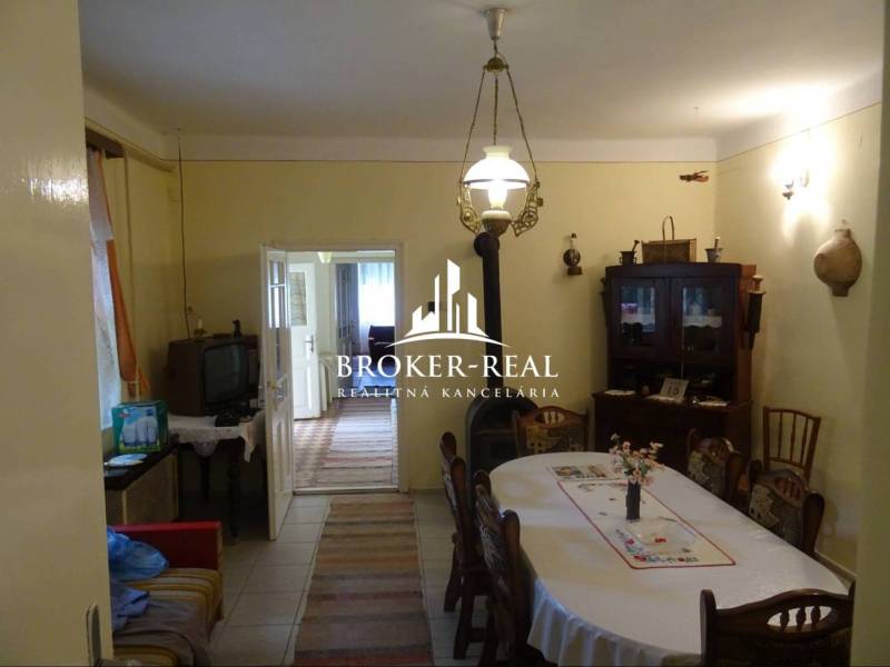 Esszimmer in einem Einfamilienhaus mit Holzmöbeln, Fernseher und Zugang zu einem weiteren Raum.