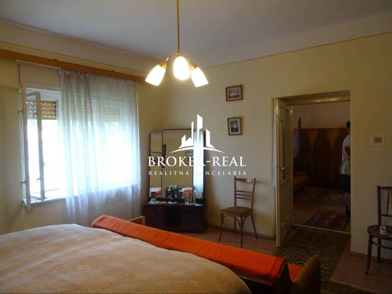 Schlafzimmer in einem Einfamilienhaus mit Holzboden, Bett, Sessel, Stühle.