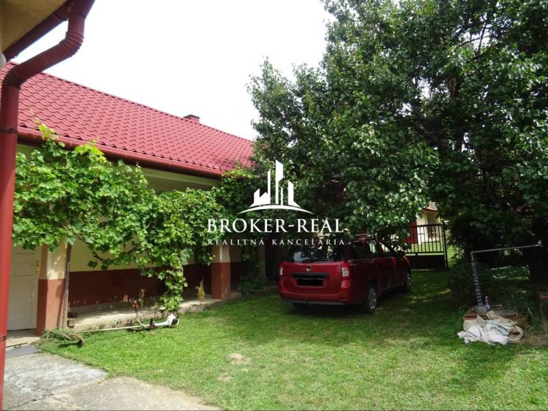 Der Garten des Einfamilienhauses in Goncruszka mit rotem Dach und einem Auto auf dem Rasen.