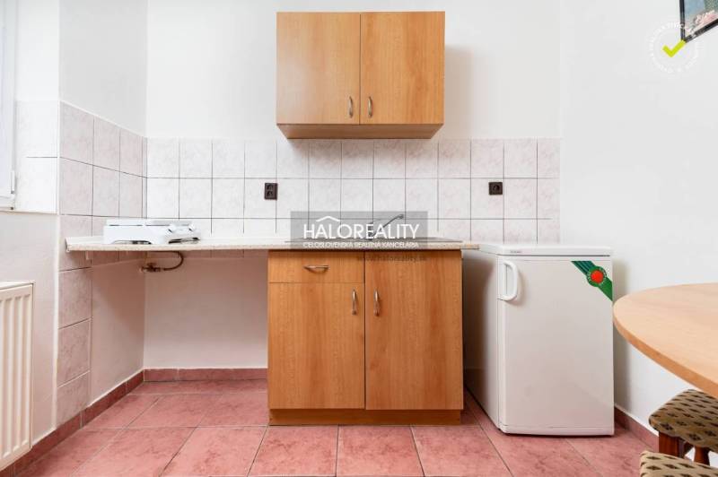 Küchenbereich mit Fliesen, Schränken und einem kleinen Kühlschrank in Hotels und Pensionen.