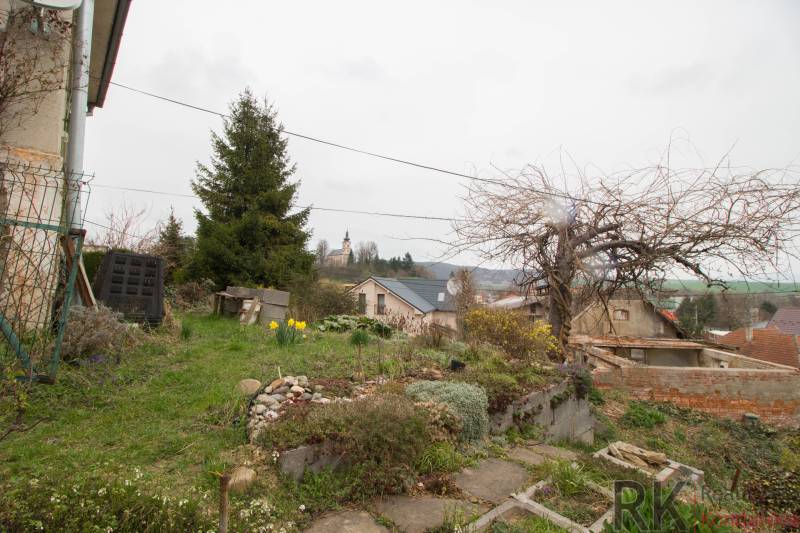 Ein Einfamilienhaus in Kostoľany nad Hornádom mit Garten, Bäumen und Blick auf die Kirche.