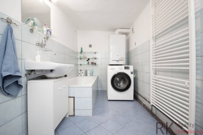 Badezimmer in einem Einfamilienhaus mit Badewanne, Waschbecken, Waschmaschine und Handtuchheizkörper.