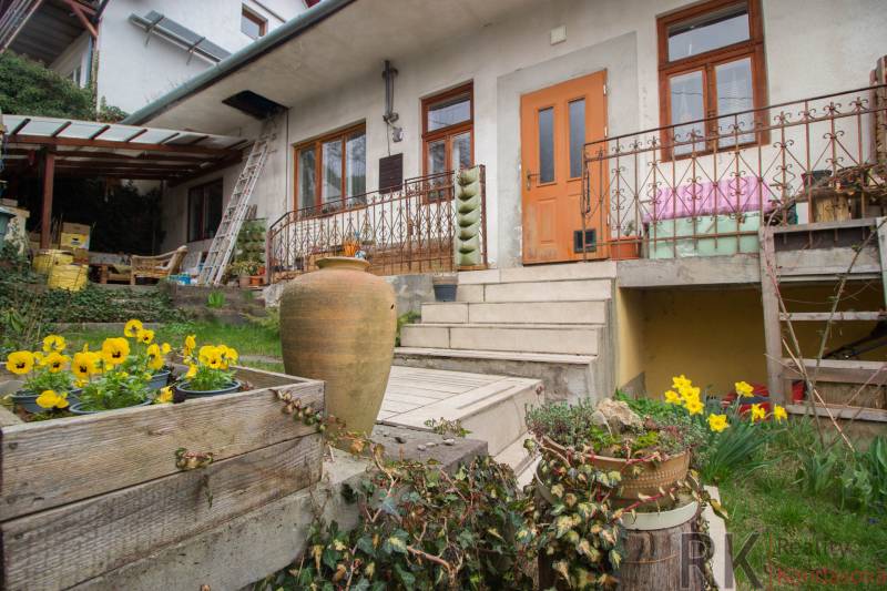 Ein Einfamilienhaus in Kostoľany nad Hornádom mit Blumen, einer Terrasse und Treppen zum Garten.