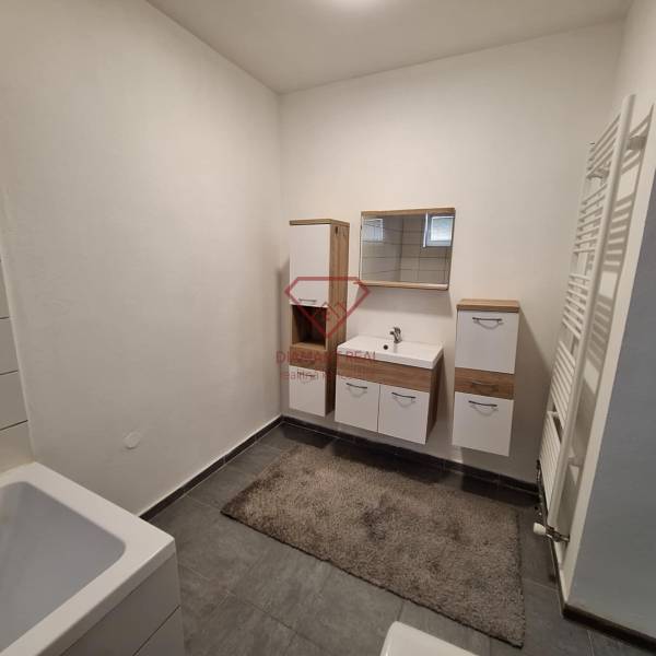 Ein Badezimmer in einem Einfamilienhaus mit weißen Möbeln und dunklen Fliesen.