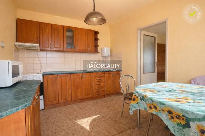 Küche in einem Einfamilienhaus mit Einbauschränken und einem Tisch mit geblümter Tischdecke.