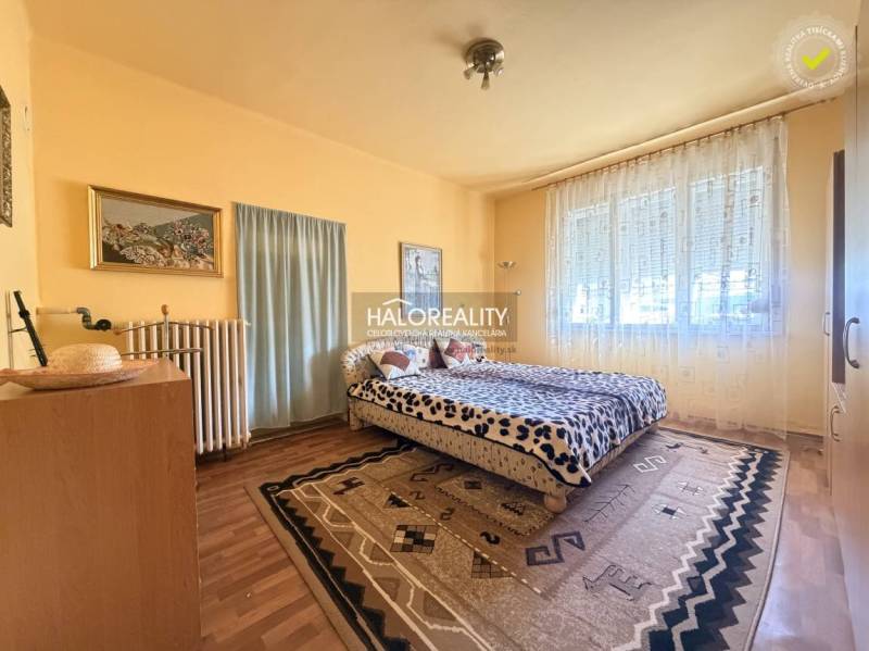 Schlafzimmer in einem Einfamilienhaus mit Holzboden, großem Fenster und Teppichen.