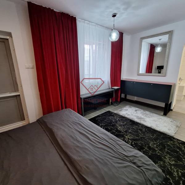 Das Innere eines Einfamilienhauses mit roten Vorhängen, einem Spiegel und einem dunklen Teppich.