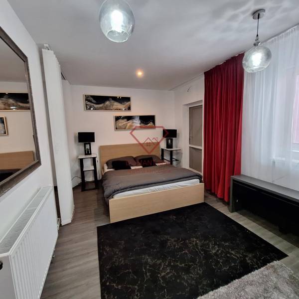 Schlafzimmer im Einfamilienhaus mit Spiegel, roten Vorhängen und Wanddekorationen.