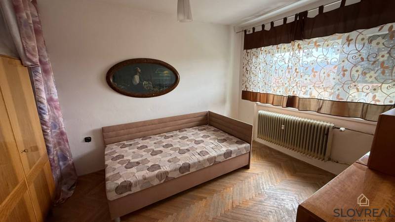 Schlafzimmer in einer 3-Zimmer-Wohnung mit Bett, Bild und Boden mit Holzdekor.