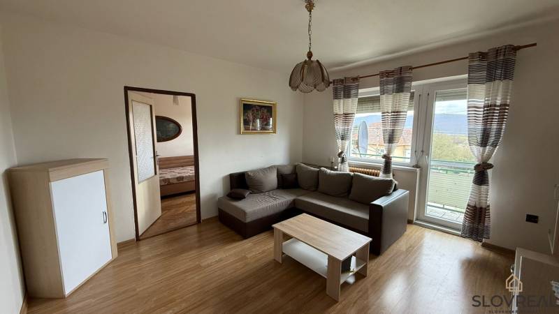 Wohnzimmer in einer 3-Zimmer-Wohnung mit Sofa und Boden in Holzoptik.