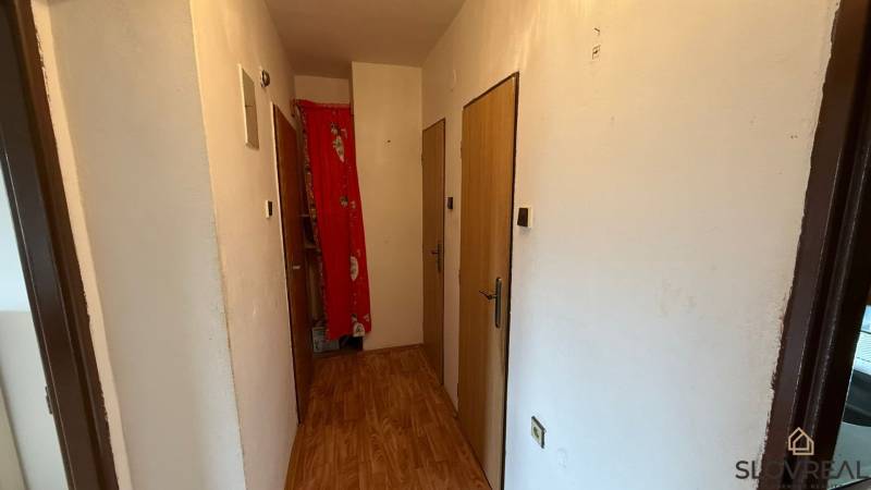 Der Flur in einer 3-Zimmer-Wohnung mit einem Boden in Holzoptik und weißen Wänden.