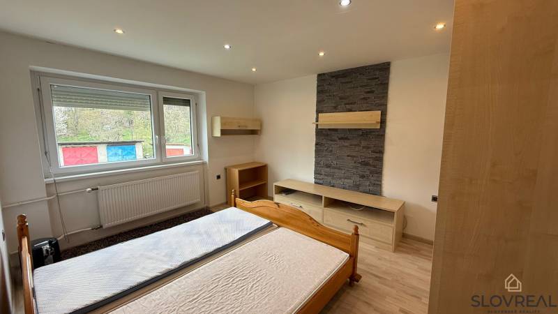Schlafzimmer mit Steinverkleidung und Holzboden in einer 3-Zimmer-Wohnung.