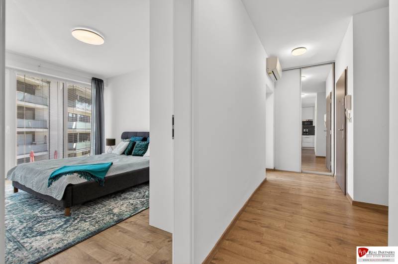 Schlafzimmer mit großem Fenster und Flur mit Holzboden in einer 2-Zimmer-Wohnung.