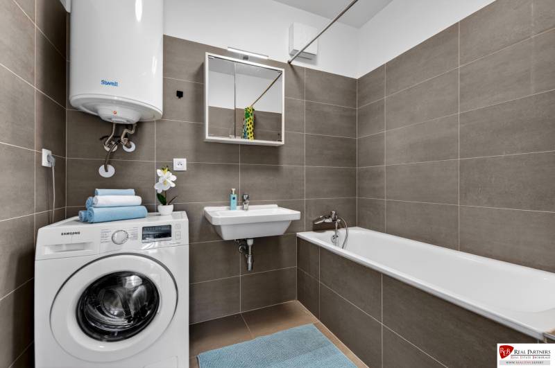 Badezimmer in einer 2-Zimmer-Wohnung mit Waschmaschine, Badewanne, Waschbecken und Gaskessel.