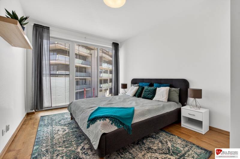 Schlafzimmer mit großem Bett, Balkontüren und Holzboden in einer 2-Zimmer-Wohnung.
