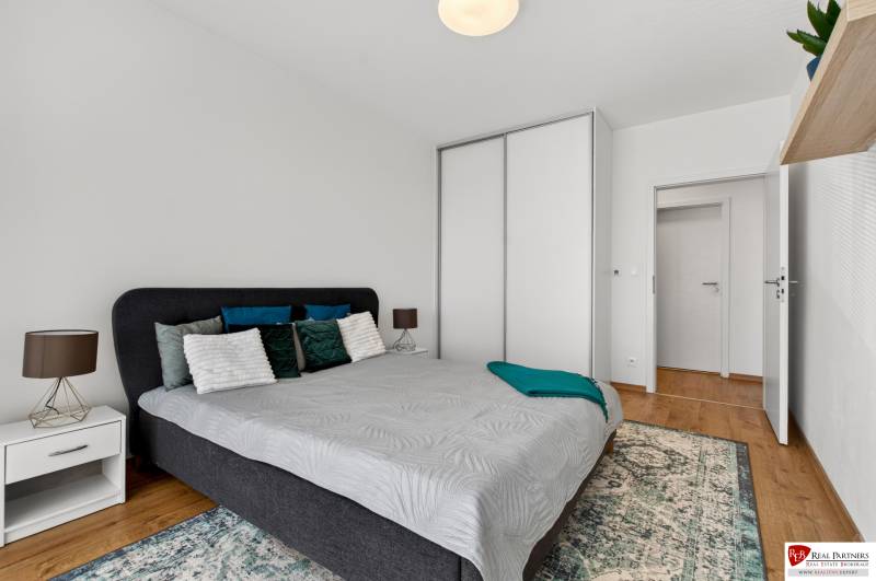 Schlafzimmer in einer 2-Zimmer-Wohnung mit Bett, Nachttisch und Schrank.