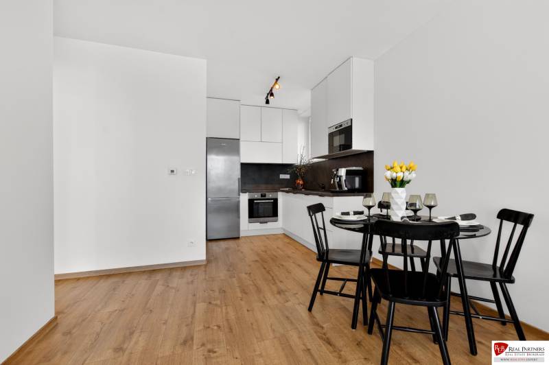 Küche mit Esstisch in einer 2-Zimmer-Wohnung, Boden mit Holzdekor.