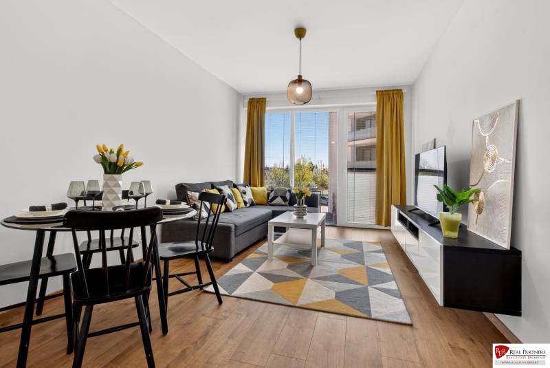 Wohnzimmer in einer 2-Zimmer-Wohnung mit Holzboden, Sofa und Esstisch.