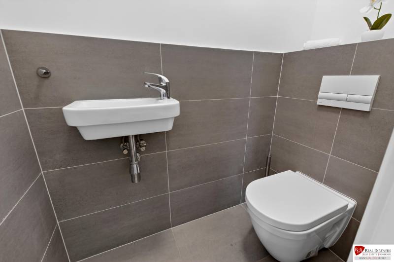 Badezimmer mit Waschbecken und Toilette in einer 2-Zimmer-Wohnung mit einfachen Fliesen.