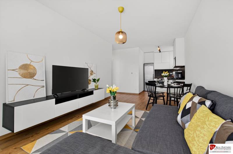 Wohnzimmer in einer 2-Zimmer-Wohnung mit Holzboden, Sofa und Fernseher.