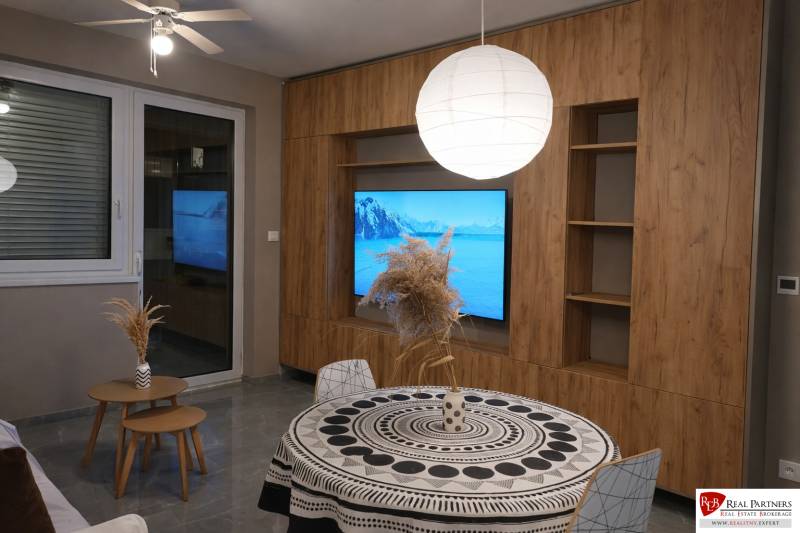Wohnzimmer in einer 2-Zimmer-Wohnung mit Holzboden und rundem Tisch.