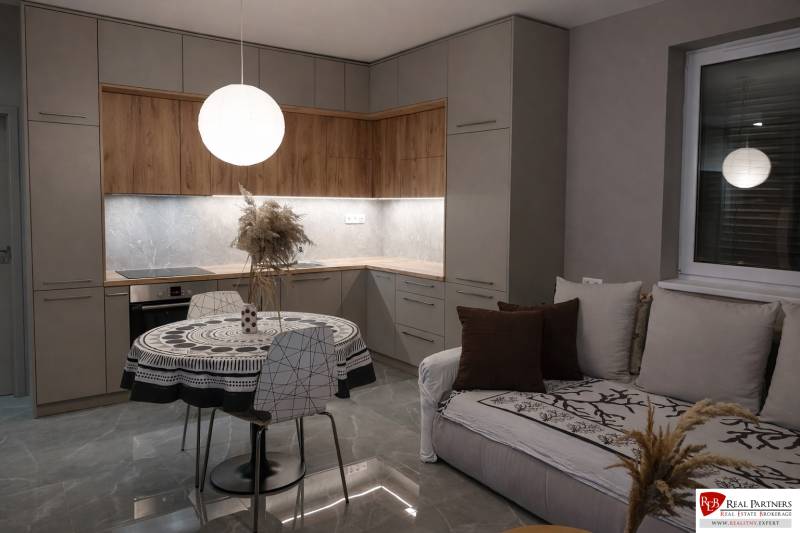 Küche in einer 2-Zimmer-Wohnung mit Holzboden und rundem Tisch.