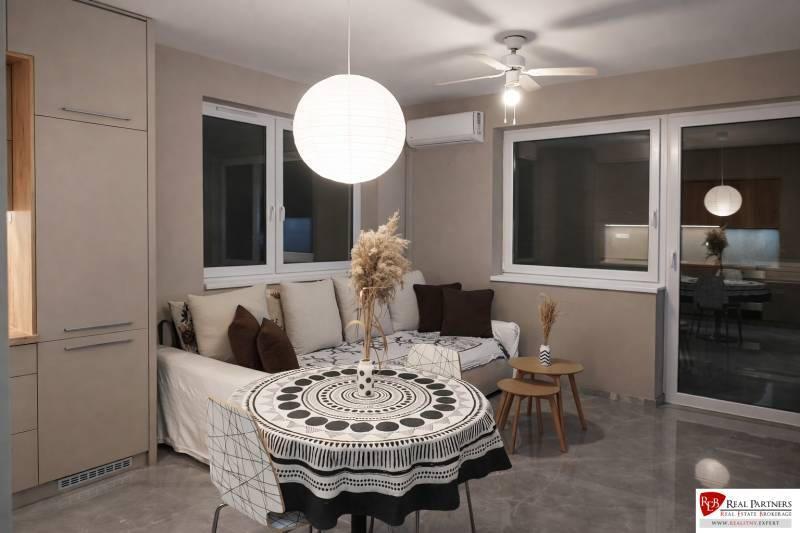 Wohnzimmer mit Sofa, rundem Tisch und dekorativer Leuchte in einer 2-Zimmer-Wohnung.