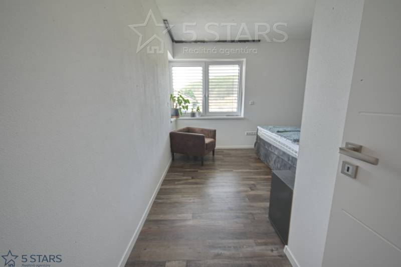 Ein Zimmer in einem Einfamilienhaus mit einem Holzboden, einem Sessel und einem Fenster.