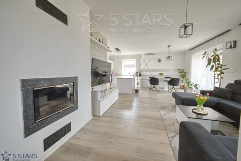Wohnzimmer mit Kamin, Fernseher und Holzboden in einem Einfamilienhaus.