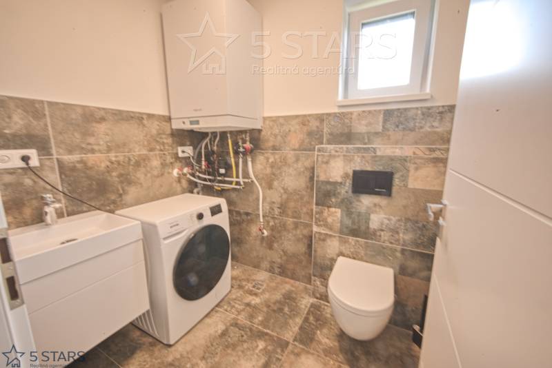 Badezimmer in einem Einfamilienhaus mit Waschbecken, Waschmaschine und Toilette.
