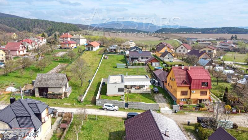 Einfamilienhäuser in der Bošianska-Straße in Neporadza, umgeben von Grün und Gebirgen.