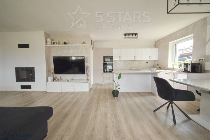 Wohnzimmer mit Küche in einem Einfamilienhaus, helle Wände, Boden in Holzoptik.