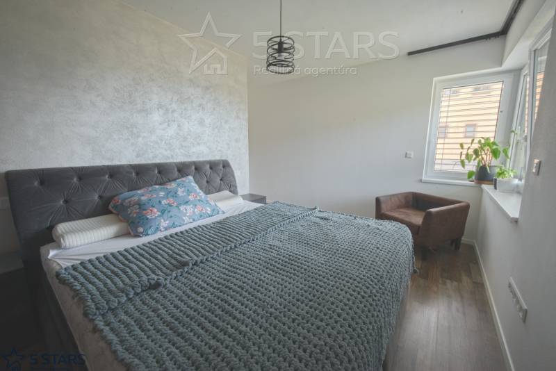 Schlafzimmer in einem Einfamilienhaus mit einem Bett mit textiler Kopfstütze und einem Boden mit Holzdekor.