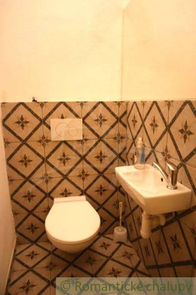 Badezimmer im Einfamilienhaus mit Waschbecken und Toilette mit dekorativen Fliesen.