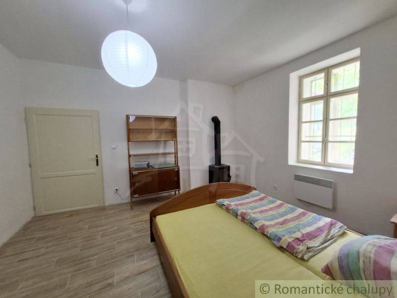 Izba v rodinnom dome s podlahou s dreveným dekorom, posteľou a pieckou.