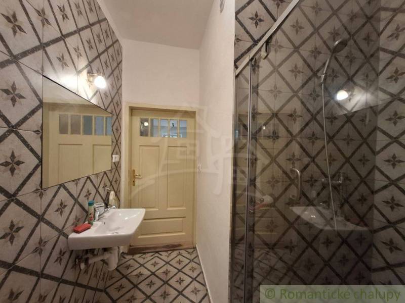 Badezimmer mit gefliester Wand, Spiegel, Waschbecken und Dusche in einem Einfamilienhaus.