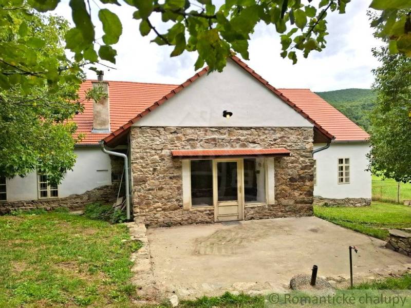 Ein Einfamilienhaus in Dobroč mit einer Steinfasade, einem traditionellen Dach und einem gemütlichen Garten.