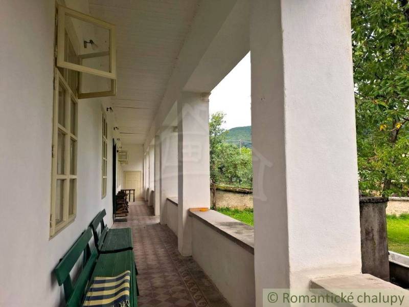 Veranda mit Bank bei einem Einfamilienhaus in Dobroč, Blick auf den Garten und die Bäume.