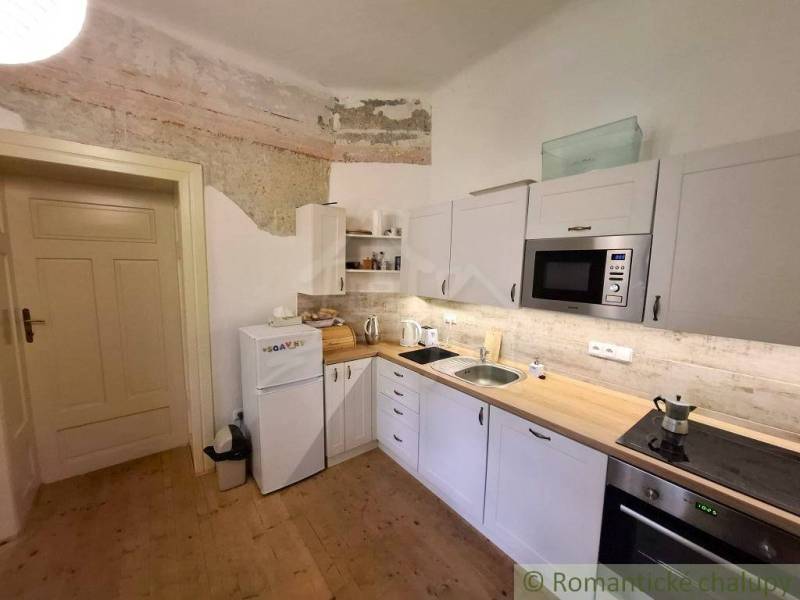 Küche in einem Einfamilienhaus mit weißen Schränken und einem Boden in Holzoptik.
