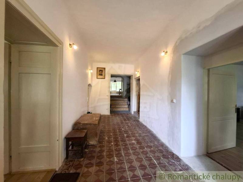 Der Flur in einem Einfamilienhaus mit gemusterten Fliesen, hell, Holztüren, Bilder an der Wand.