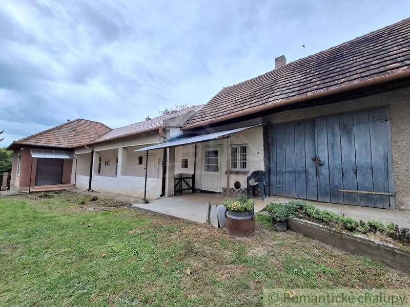 Ein Einfamilienhaus in Mužla mit traditioneller Fassade, Veranda und einem üppigen Garten.