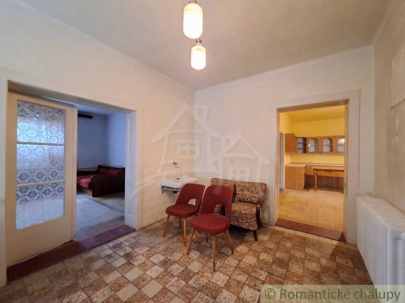 Interieur eines Einfamilienhauses mit Sesseln, Waschbecken, Küche und zwei offenen Türen.