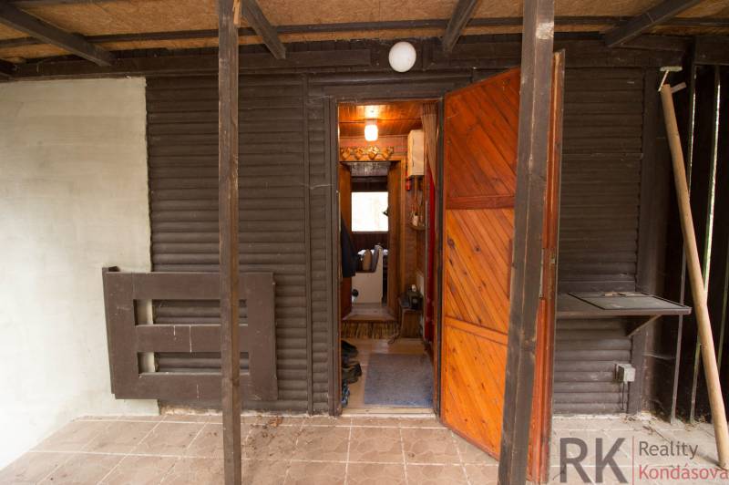 Eingang zur Hütte mit aufklappbaren Holztüren und Veranda auf Freizeitgrundstücken.
