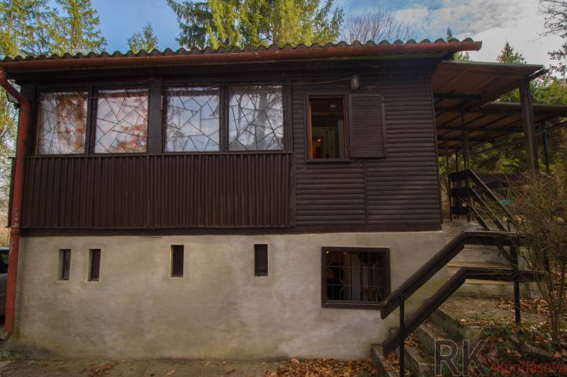 Eine Holzhütte auf Erholungsgrundstücken in Holčíkovce, umgeben von Grün und Bäumen.