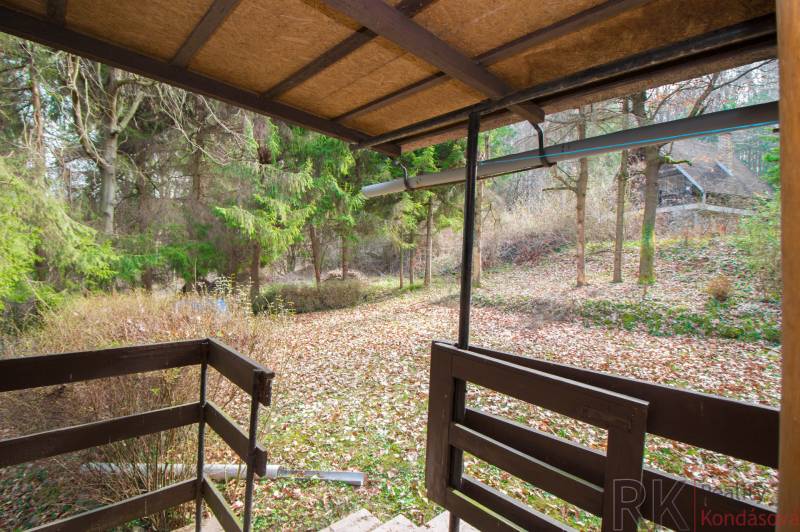 Blick von der Terrasse auf die Erholungsgrundstücke in Holčíkovce mit Herbstlaub und Bäumen.