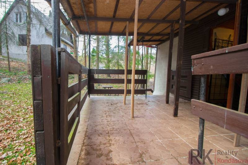 Eine Holzterrasse umgeben von Bäumen auf den Erholungsgrundstücken in Holčíkovce.