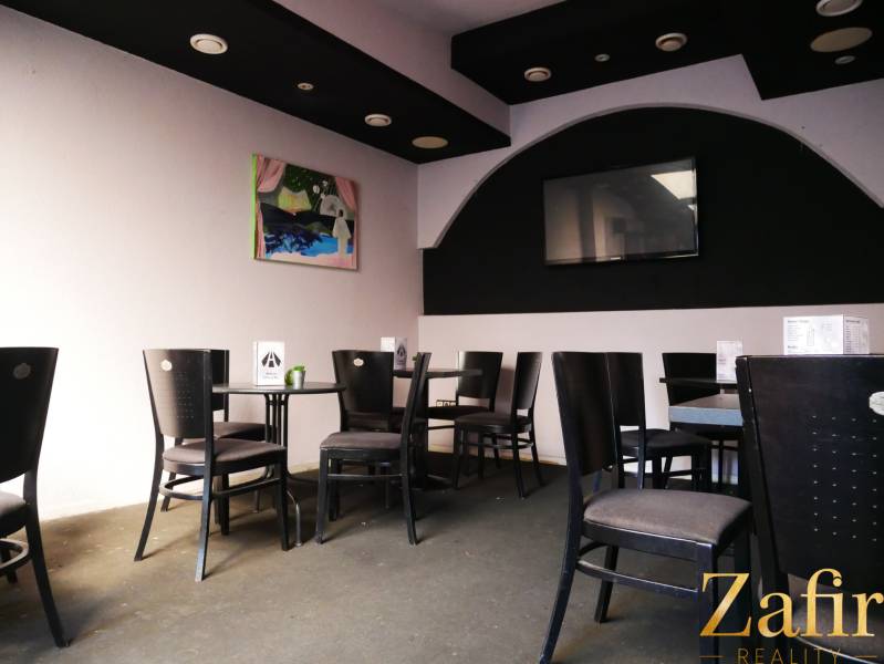 Gasträume mit schwarzen Stühlen, Kunst an der Wand und einem Fernseher.